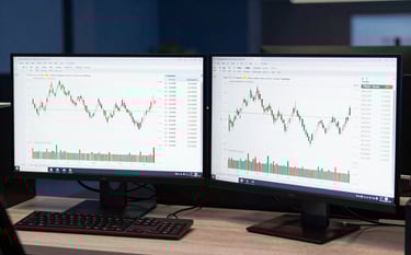 A high-end trading desk in an International Financial Market setting with dual monitors displaying clean financial data and price action charts, illuminated by soft natural light and deep navy blue ambient tones.