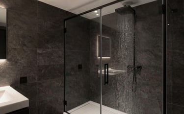 A high-end, luxurious modern bathroom in a Dutch home. Featuring large format dark charcoal tiles, a minimalist walk-in rain shower with a seamless glass partition, and premium matte black hardware. Soft recessed lighting creates a sophisticated atmosphere. Northern European / Dutch interior design.