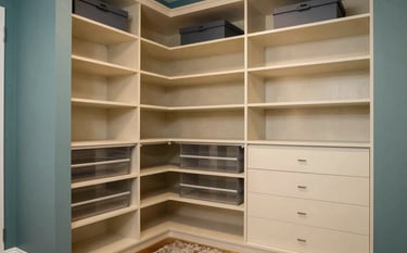 A high-end walk-in closet system in a North American / US (Florida) master suite, featuring dusty teal accents and custom warm cream organization units.