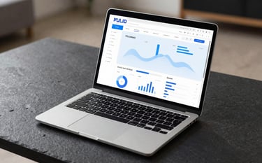 A high-end silver laptop open on a dark slate surface. The screen shows a modern, responsive website dashboard with soft blue data visualizations. The environment is a professional, minimalist workspace in Brno with soft, natural lighting.