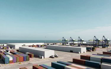 A wide-angle professional photograph of a modern logistical hub or container terminal during the day. The scene shows organized logistics infrastructure with a clear blue sky. The composition is clean and efficient, emphasizing global movement and reliability. North American coastal setting with deep teal and soft white tones.