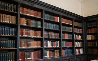 A serene and elegant school library in West London, with dark charcoal bookshelves and a sense of deep intellectual heritage. Western European / British architectural details. Soft, warm lighting creates a nurturing atmosphere of integrity and faith.