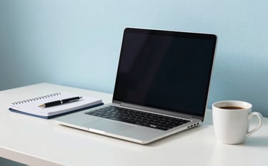 A clean, minimalist desktop workspace in a North American / US office setting. A laptop, a notebook with a professional pen, and a cup of coffee sit on a desk. The lighting is bright and natural, incorporating soft cerulean blue accents and pale frost blue walls.