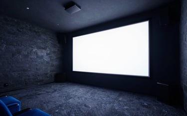 Wide-angle photograph of a sophisticated home cinema room with dark slate walls and ambient electric indigo lighting, featuring a huge screen with 4K clarity.