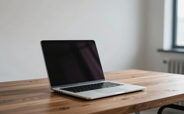 A high-end, minimalist workspace featuring a slim silver laptop on a polished wooden desk. The background is softly blurred with elegant mist white walls and a hint of soft steel blue decorative elements. Natural light creates a professional and clean atmosphere.