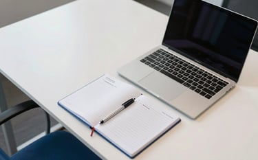 An aerial view of a professional, modern desk in a Brazilian corporate hub. The arrangement is organized and clean, featuring a notepad with professional notes and a sleek laptop. The style is forward-thinking and trustworthy, utilizing the palette of off-white and medium blue for a sense of calm authority.