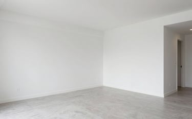 An interior shot of a newly renovated luxury apartment. The space features clean white walls, light gray porcelain tile flooring, and modern lighting. The aesthetic is professional and reflects high-quality European standards.