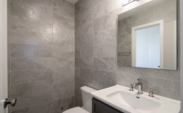 A stunning, modern bathroom remodel in a New Mexican residence. Features elegant silver-gray tiles, professional plumbing fixtures, and clean architectural lines. Soft, bright natural lighting.