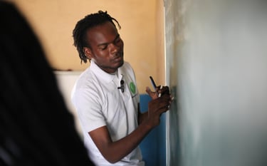 a man in a white shirt is writing on a blackboard