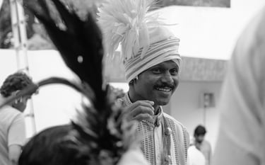 Smiling Indian man wearing a traditional turban and ethnic attire in a black and white portrait.