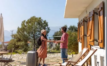 A happy woman traveler with a suitcase arriving at a sunny vacation rental villa to meet her host.