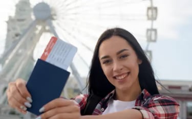 Smiling woman holding a blue passport and airline boarding pass in front of a white ferris wheel.