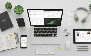 A top-down view of a marketer's desk with a laptop showing affiliate tools and various tech accessor