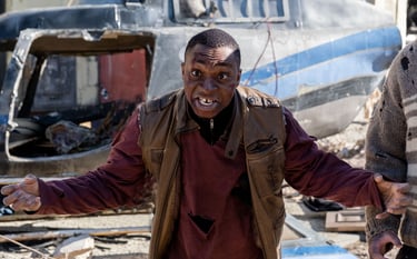 Actor dressed as a zombie leaning forward and staring straight at camera with arms wide open
