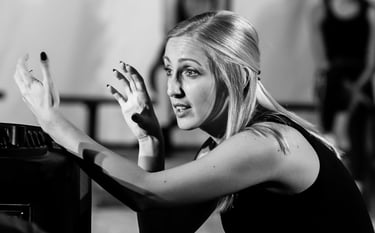 Young lady explaining to the director using her arms looking off to the left of image