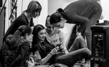 A group of performers reviewing a video on a mobile phone during a break