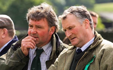Two men in outdoor clothing deep in discussion looking off to the left of the image