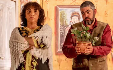 Two actors one holding out a plant to the other as peace offiering