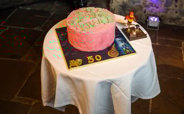 Pink birthday cake on display table in event hall, photographed by Fred Art Studio.