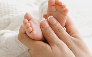 a woman holding a baby's feet up to her feet