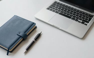 A clean, modern top-down view of a minimalist desk with a high-end laptop, a structured leather notebook, and a sleek pen. The lighting is soft and professional. Accents of #1A2E2F and #476A6B are visible in the accessories. The atmosphere is strategic and intentional.