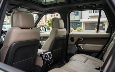 Interior of a luxury SUV, showing spacious leather seats and high-tech amenities. Soft natural lighting entering through tinted windows. Modern and clean aesthetic. South American / Brazilian context visible in the urban background through the glass.