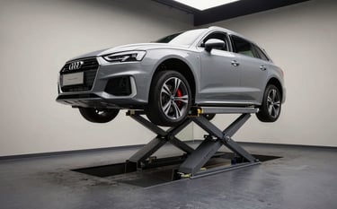 A professional wide shot of a modern, clinical-style automotive workshop with a dark slate gray floor. A premium silver Audi is elevated on a lift. The lighting is focused and dramatic, highlighting mechanical precision. Crisp off-white walls in the background.