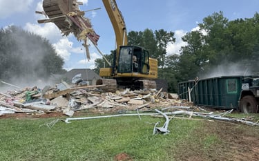 Excavator loading demolition debris in dumpster