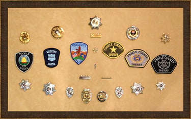 Collection of Tooele City and County sheriff and police patches and gold law enforcement badges.