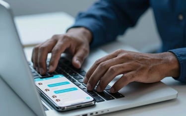 Close-up of hands typing on a modern laptop keyboard next to a smartphone showing customer chat notifications, South American corporate setting, colors dominated by light blue and dark blue.