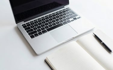 A minimalist and professional top-down shot of a clean office desk featuring a high-end laptop, a white notebook, and a sleek pen. The scene is bathed in natural morning light, using a palette of #F7FAFC and #A0AEC0 to emphasize efficiency and modern business standards.