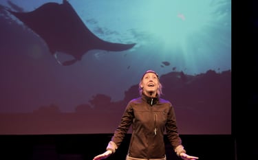 Julia Duchaussoy sur scène avec une raie Manta en arrière plan