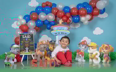 a young boy sitting on a table with balloons and balloons