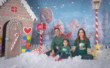a family posing for a photo in front of a gingerbread house