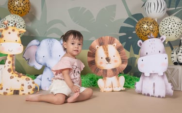 a baby girl sitting on a table with a bunch of stuffed animals