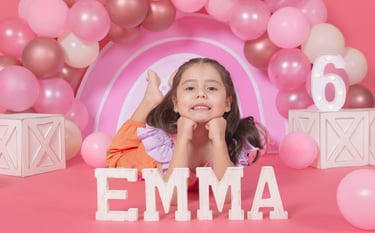 a little girl is posing for a photo in front of a pink arch arch arch