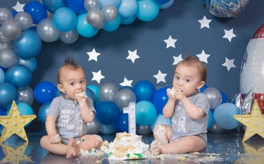 two babies are sitting on a table with balloons and balloons