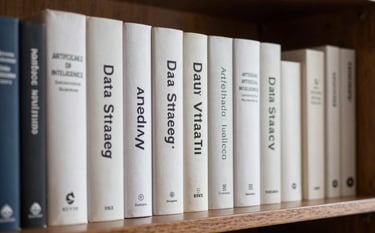 A sophisticated library shelf in a Southern European / Spanish study. Close-up on a selection of hardcover books about Data Strategy and Artificial Intelligence, with lighting that emphasizes the clean textures and Ice White tones.