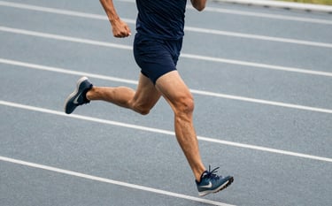 Action photography of an athlete running on a slate grey track, wearing navy blue sportswear. Sharp focus, energetic lighting, and a modern sports marketing aesthetic.