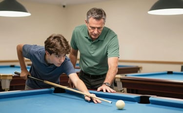 A professional photography shot of a mentor in a sage green polo shirt showing a teenage student how to bridge a cue stick on a high-quality billiard table. The setting is a bright, clean community center with warm cream walls and professional lighting.