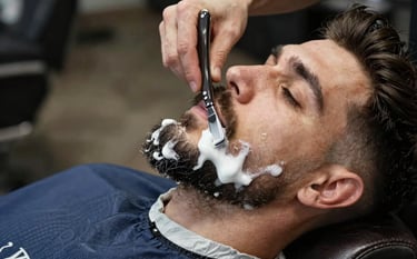 Detailed shot of a professional barber grooming a man's beard using a traditional straight razor. White foam, a warm towel nearby, masculine leather textures, European / Romanian style, Slate Blue and Deep Black color accents.
