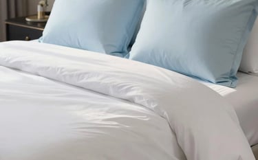 Close-up of a perfectly made bed in a luxurious North American / US estate bedroom, showcasing crisp, flawlessly ironed alabaster white linens and soft pastel blue accent pillows. A gentle, warm sunlight creates a sparkling, pristine atmosphere. High-end hospitality aesthetic, immaculate and extremely clean, professional commercial photography.