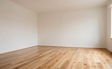 An empty living room with polished light wood floors and soft off-white walls. The space looks immaculate after a deep clean, with bright, natural lighting emphasizing the fresh, organized aesthetic of a move-out service.