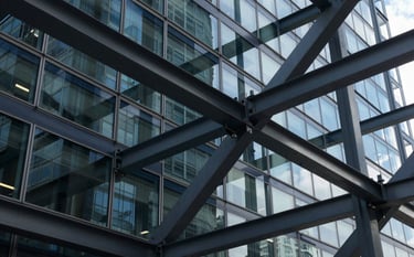 Abstract photography of a complex network of glass and steel beams reflecting deep navy and charcoal grey, symbolizing robust systems integration in a modern North American / Global corporate environment.