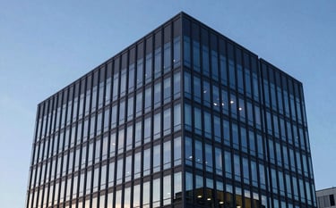 A sophisticated architectural photograph of a sleek North American office building exterior during the blue hour. Reflections in the glass show a clean sky. The atmosphere is quiet, stable, and profoundly professional, using sky blue and deep slate tones.