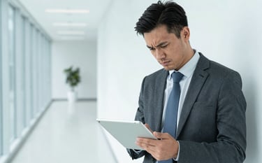 A North American business professional looking relieved and confident while using a digital tablet in a bright, modern corporate environment. The composition is clean and minimalist, highlighting a path to financial stability with light blue accents.