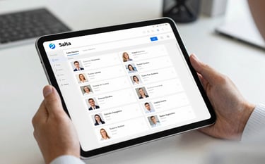 Close-up photography of a professional hand in a white shirt holding a digital tablet in a bright office in Salta, Argentina. The tablet displays a clean, minimalist CRM interface with organized client profiles. Sharp focus, professional lighting, reflecting corporate authority.