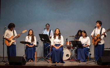 Photography of a modern music team with instruments on a stage in a Central American / Costa Rican sanctuary, warm atmospheric lighting, muted steel blue backdrop, ghost white and deep navy blue tones, spiritual and inviting mood.