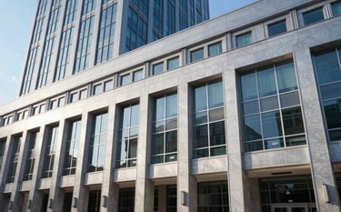 The exterior facade of a modern, institutional commercial building in a North American / US financial center. The building features clean glass and steel architecture. The lighting is crisp morning light, reflecting a light steel blue sky, emphasizing stability and strength.