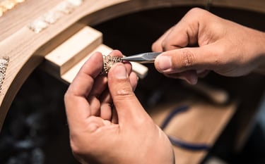 Joyero utilizando pinzas de punta fina para elaborar joyería artesanal de filigrana en oro.